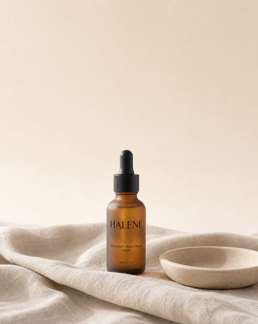 HALENE No. 01 Bakuchiol + Beta-Glucan Serum in frosted amber glass on natural linen beside a ceramic dish