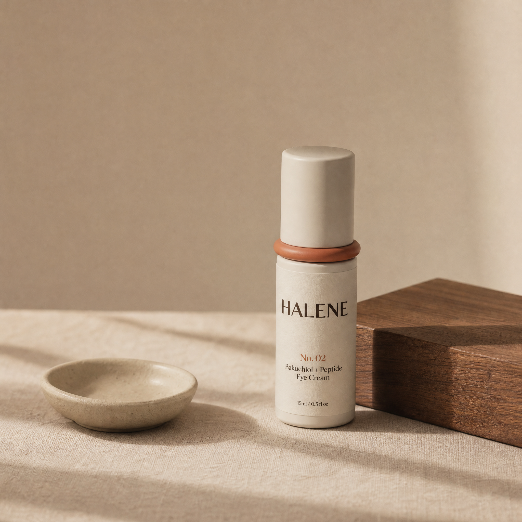 HALENE No. 02 Bakuchiol eye cream on natural linen with a ceramic dish and walnut block