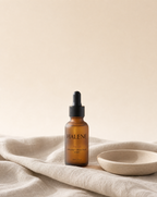 HALENE No. 01 Bakuchiol + Beta-Glucan Serum in frosted amber glass on natural linen beside a ceramic dish