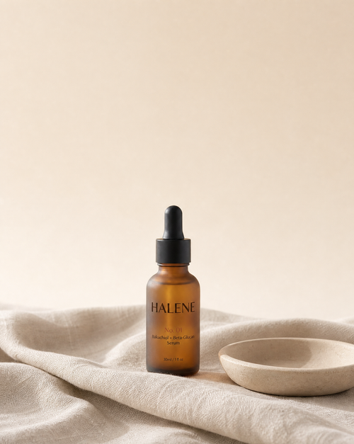 HALENE No. 01 Bakuchiol + Beta-Glucan Serum in frosted amber glass on natural linen beside a ceramic dish